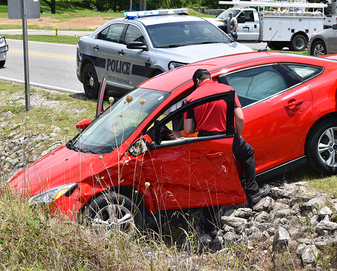 Paramedics help an injured woman from her vehicle to a stretcher.