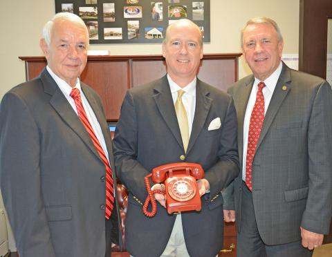 Congressman Robert Aderholt, center, holds the iconic red phone from which the first 9-1-1 call in the nation was made after he and Alabama Speaker of the House Mac McCutcheon, right reenacted that historic phone call.  With them is Haleyville Mayor Ken Sunseri, left.