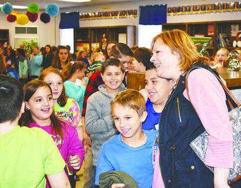 Students give Addison Elementary Media Specialist Lynn Tuggle hugs once she makes her way into the library.