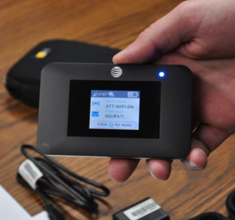 One of the libraries' new WiFi hotspot devices, now available for checkout. Its case and charger may be seen in the background.