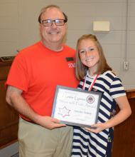 Middle School Principal Bo Wilcoxson presents the Howie Lyons Serve with Pride award to student Aynelise Vickery.