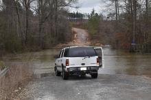 Splunge Creek flows out of its channel and across County Road 339 with the recent rains. The Chevrolet Tahoe shown has been extracted from the creek after occupants tried to cross.